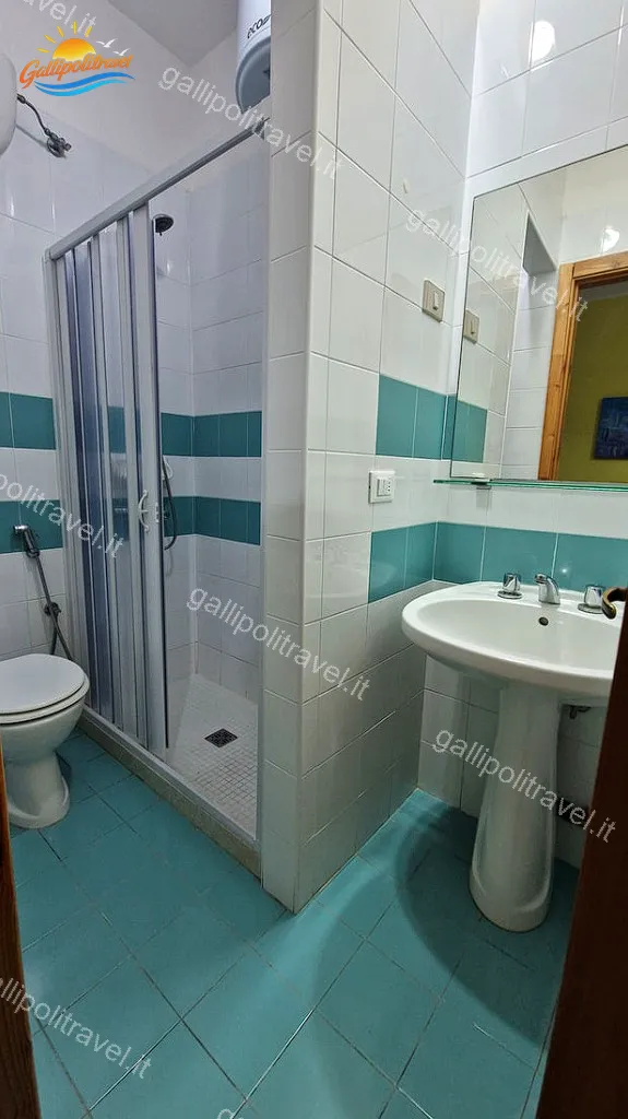 Bagno del Bilocale La Vela con piastrelle azzurre e doccia a Gallipoli
