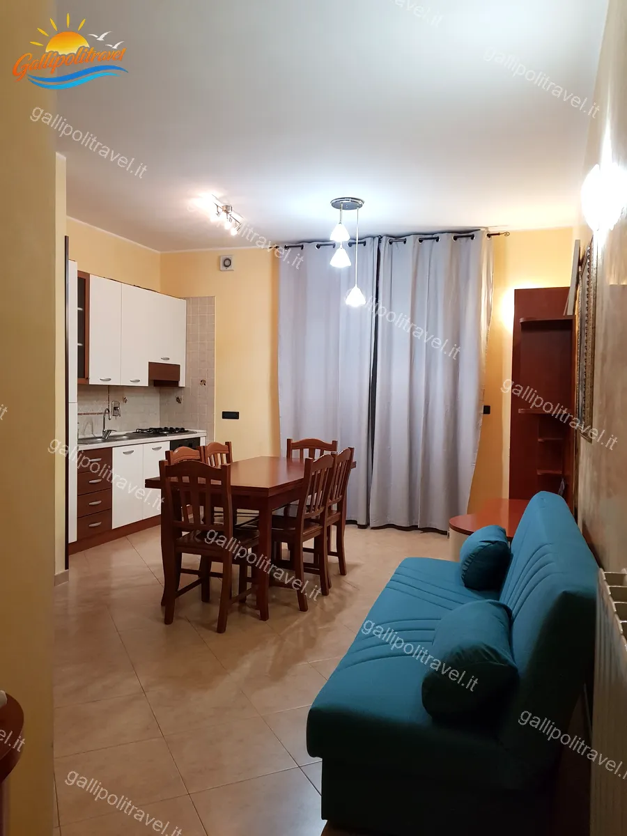 Soggiorno del Trilocale D1/3 con divano turchese e tavolo in legno a Gallipoli