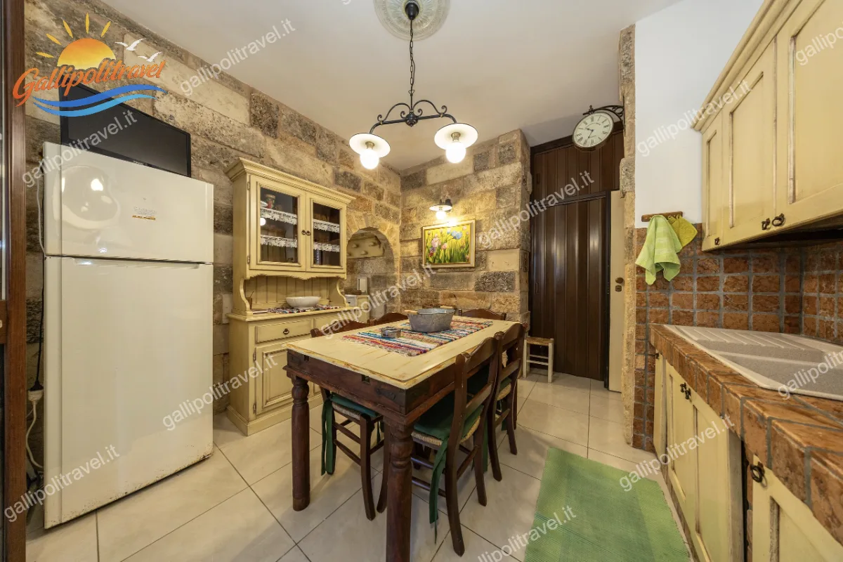 Accogliente zona giorno caratterizzata da suggestive pareti in pietra a vista, grande tavolo da pranzo centrale e mobile credenza in stile rustico