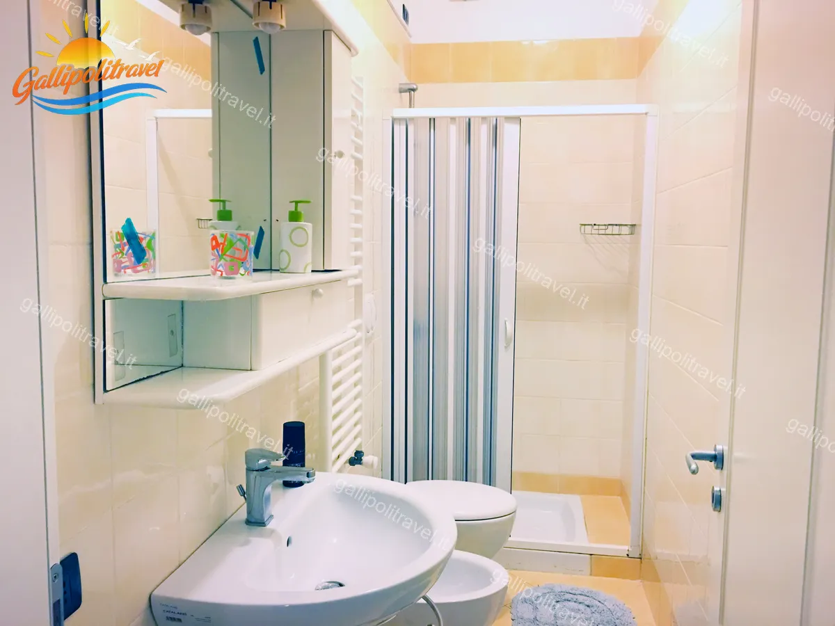 Primo bagno del Trilocale H2/2 con piastrelle beige, doccia e scaldasalviette