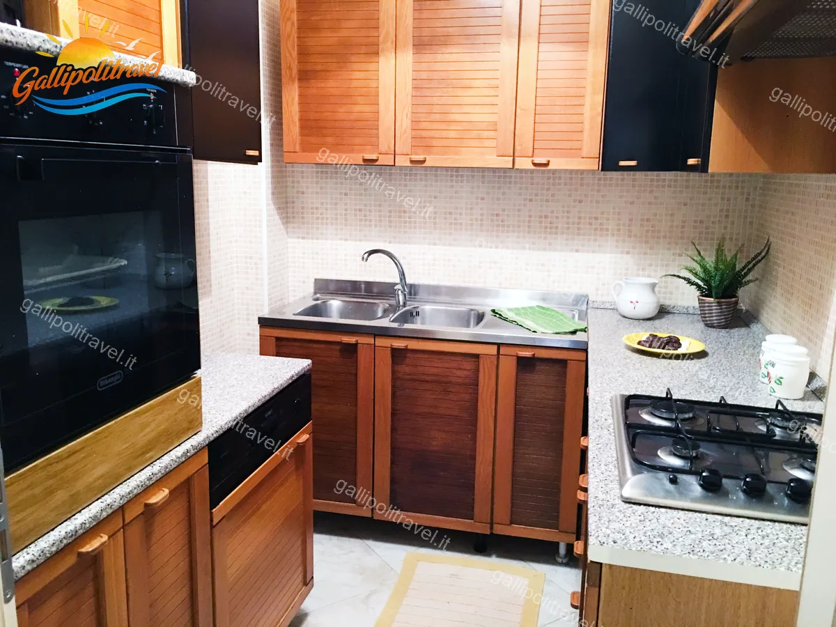 Cucina ad angolo del Trilocale H2/2 con piano in granito, forno e ante in legno