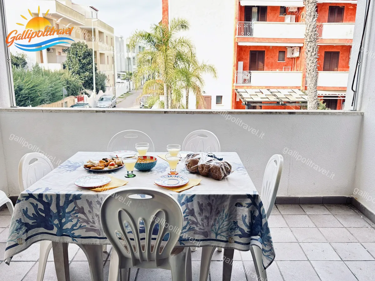 Balcone del Trilocale Mimosa a Baia Verde con tavolo apparecchiato e vista sulle palme