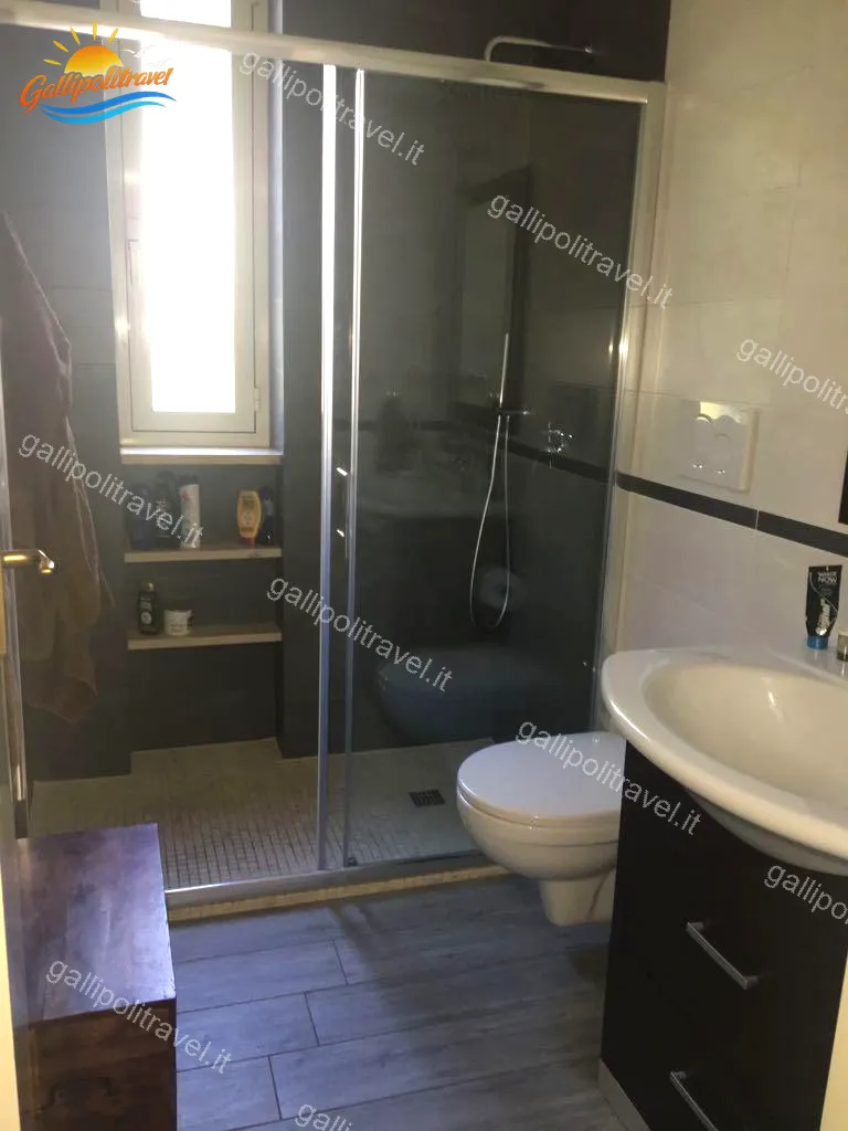 Bagno moderno del Trilocale Girasole con doccia scorrevole e piastrelle scure