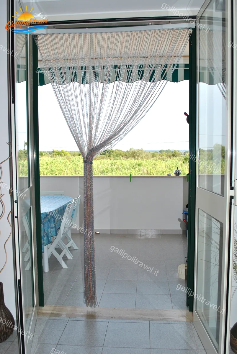 Ingresso sul balcone del Trilocale Girasole con tende a fili e vista sulla vegetazione