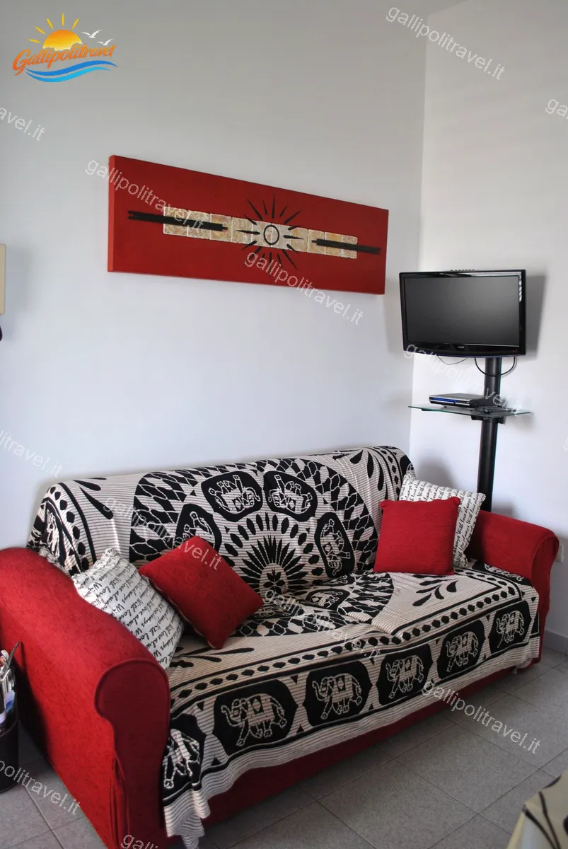 Soggiorno del Trilocale Girasole con divano rosso, quadro decorativo e TV
